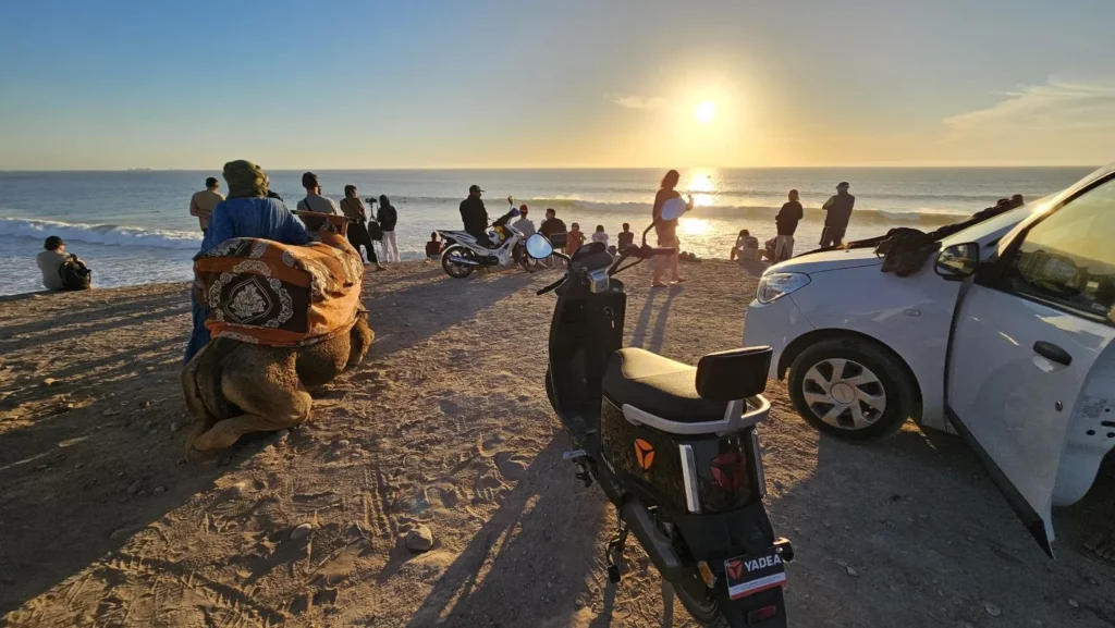Sonnenuntergang am Banana Point mit einem Kamel und Menschen, die das Meer beobachten, Aourir