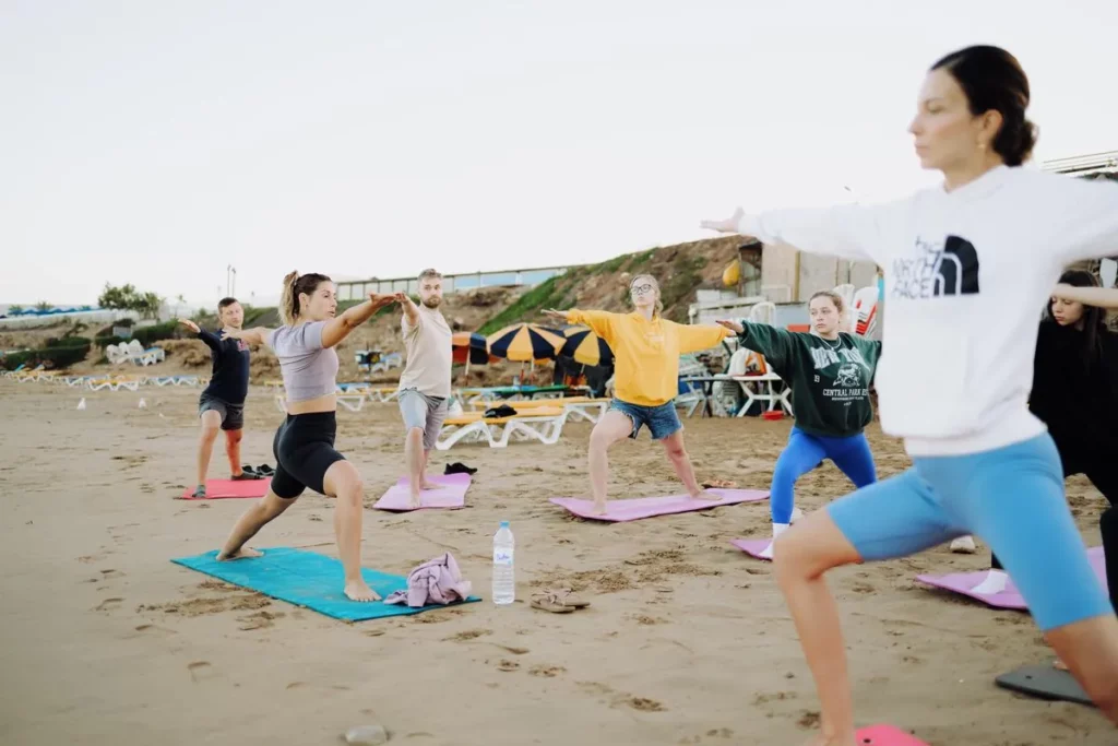 Yoga class in warrior pose on the beach at our surf camp in Taghazout