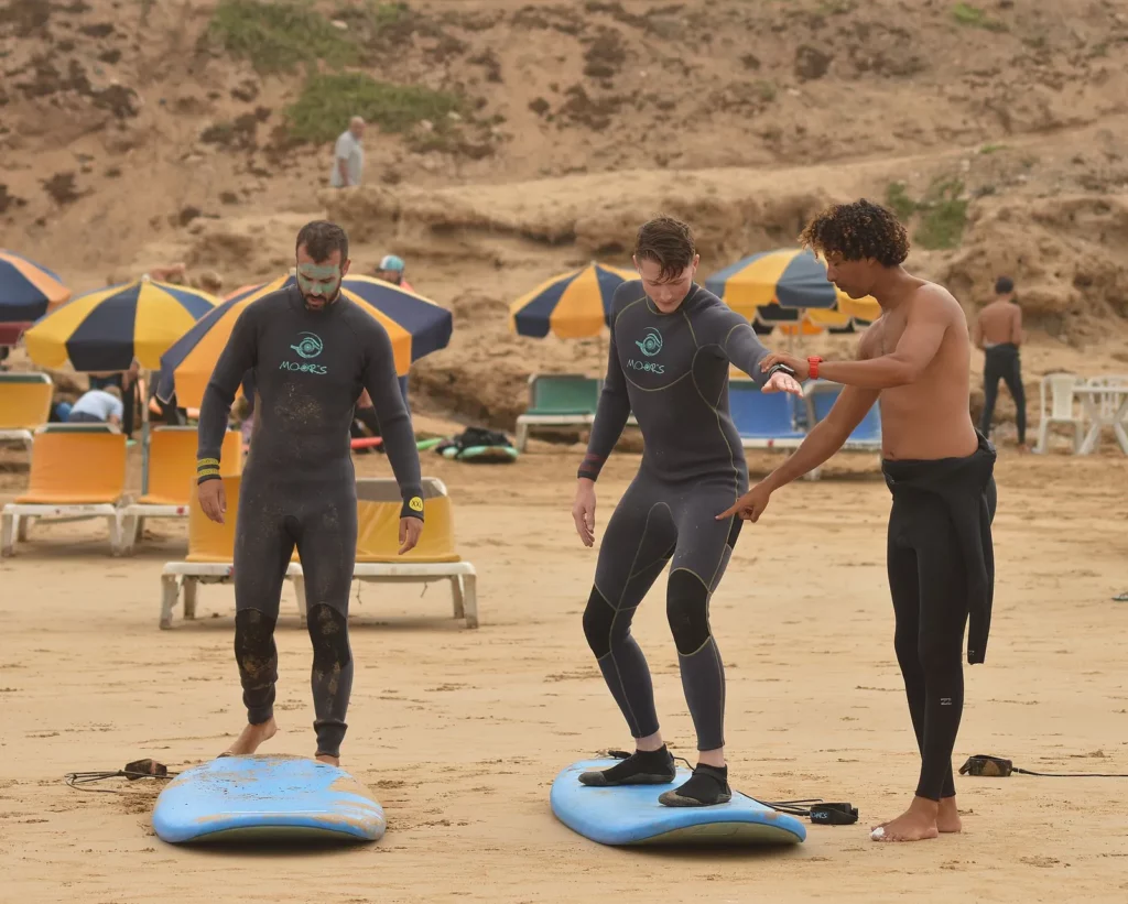 Surf instructor teaching students the pop-up on the sand in Tamraght