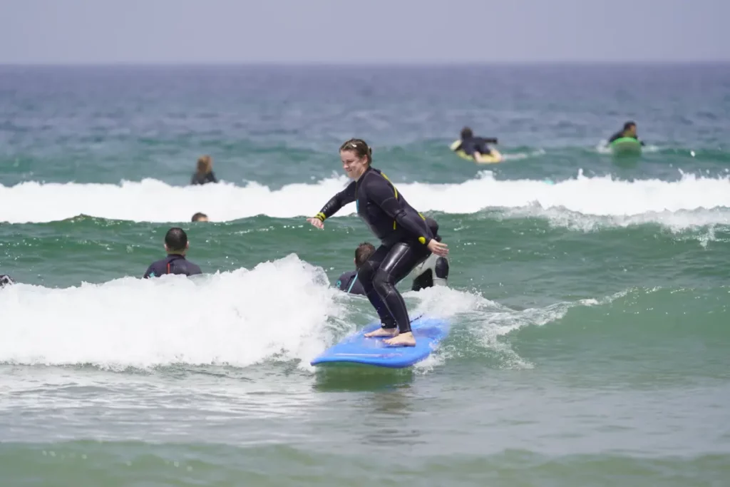 Surfer riding a green wave on a blue board during a surf lesson in Taghazout