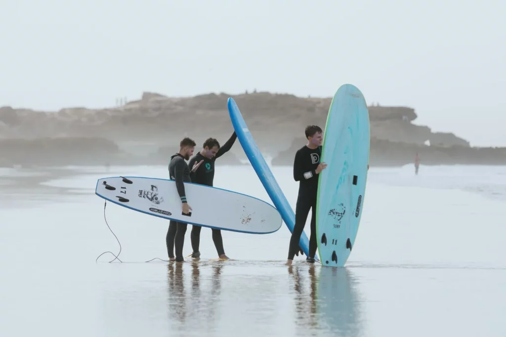 Surfers standing with their boards on a misty morning beach near Tamraght
