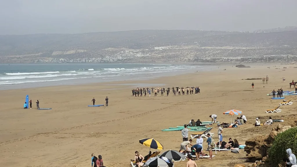 Wide view of Tamraght beach with surf lessons on the sand, Morocco